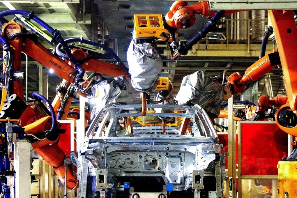 Robotic arms work at an automobile assembly