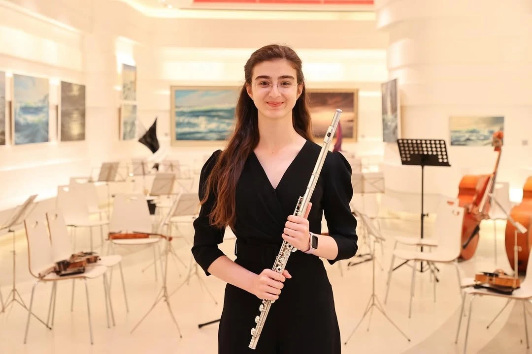 Duru Bulam posing with her flute next to the audience seats, and another image of her playing the flute.