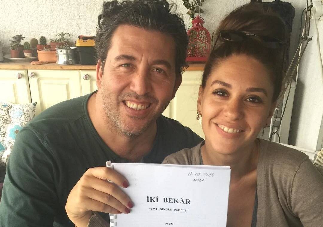 Evrim Alasya and Emre Kinay pose holding the script for the play two single people