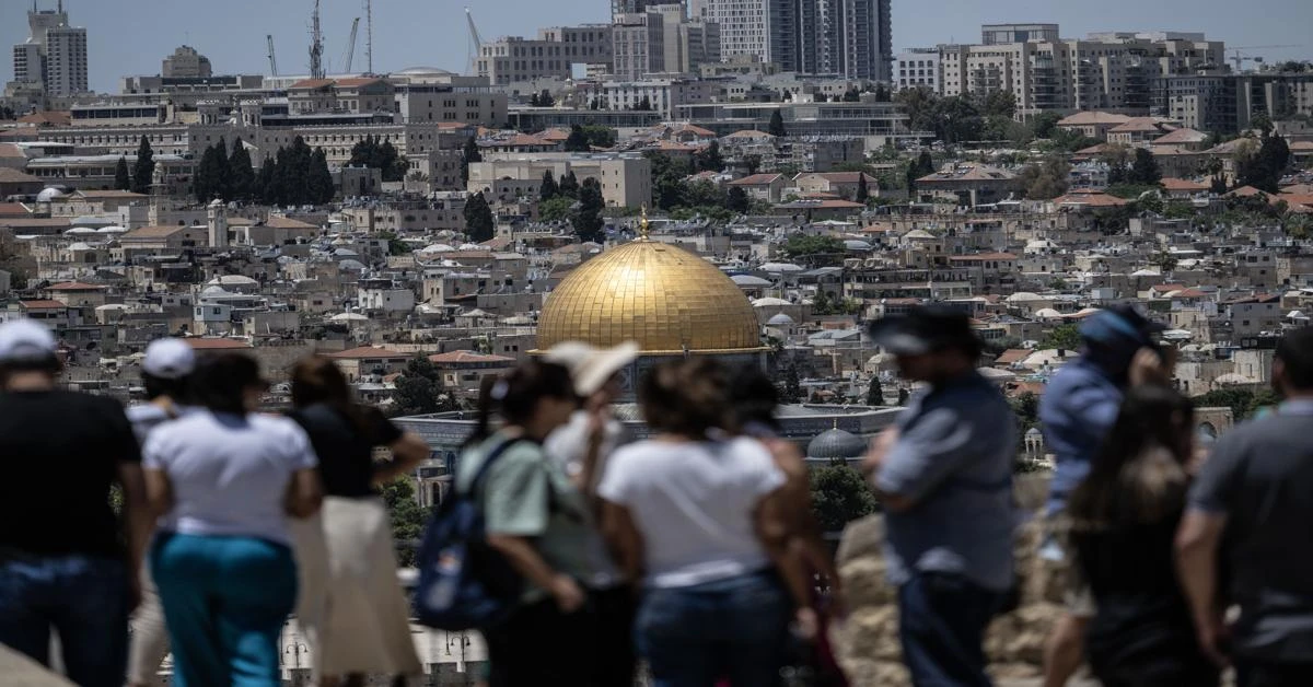 An Israeli illegal settler waves an Israeli flag as he enters Al-Aqsa Mosque