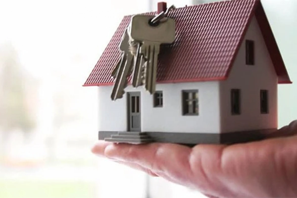 File photo shows a small model of a house placed on a person's palm, with a set of keys hanging above it. (IHA Photo)