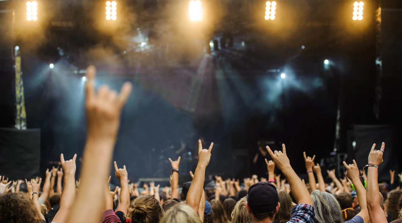 A crowd at a concert with hands raised, showing the heavy metal rock sign - Headbangers' Weekend