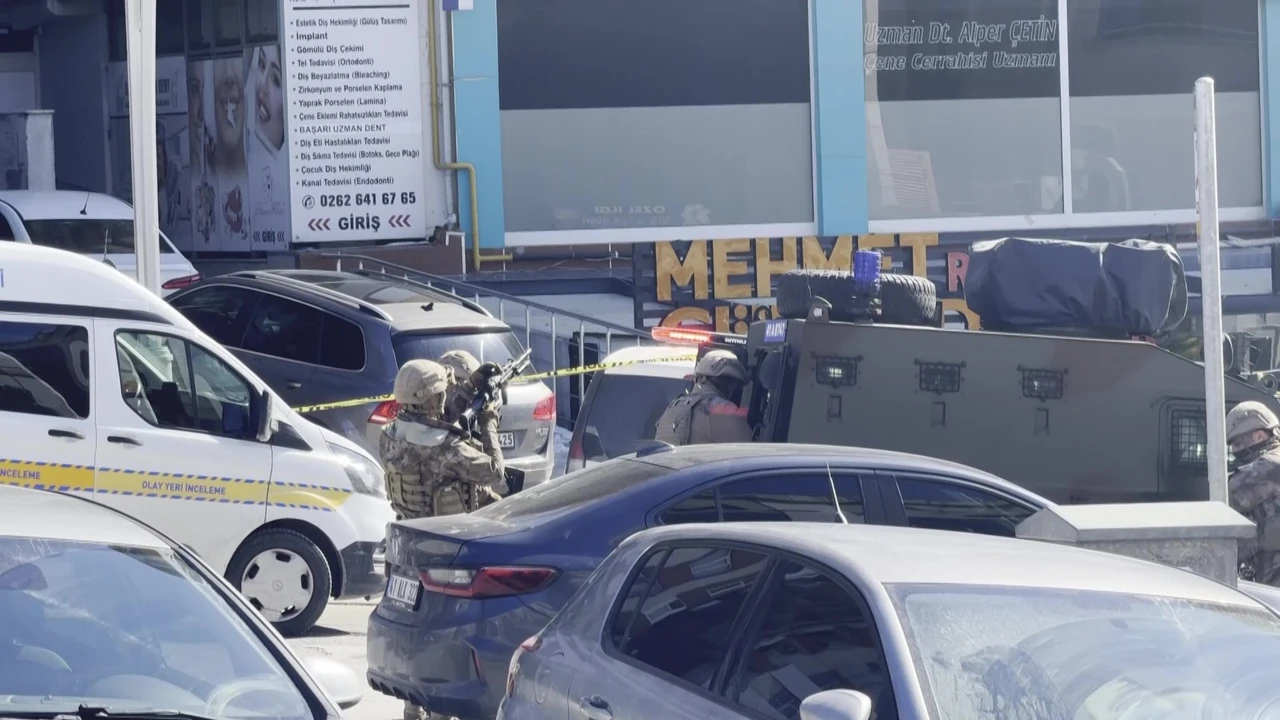 Photo shows Turkey special forces officers in tactical gear crouch behind parked cars next to an armored vehicle outside a medical facility. Yellow police tape and several civilian vehicles are visible in the foreground