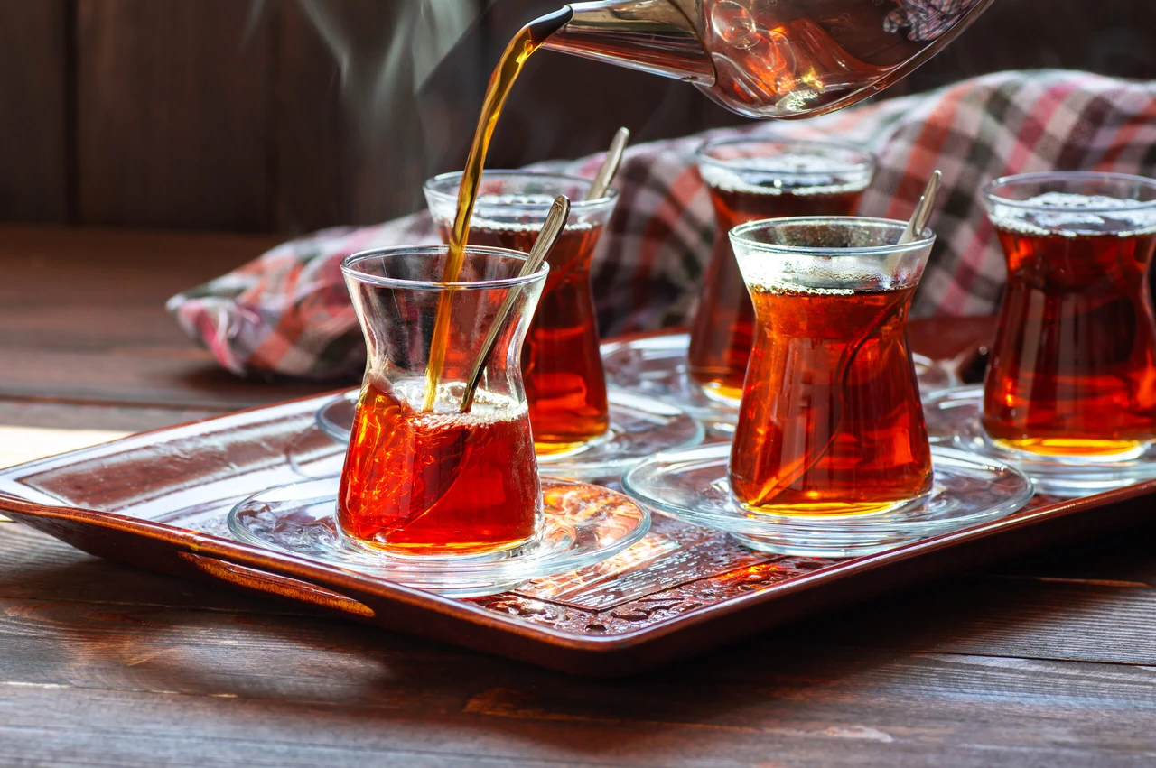 A glass cup of freshly brewed Turkish black tea, poured from a teapot—warm, aromatic, and traditional. (Adobe Stock Photo)