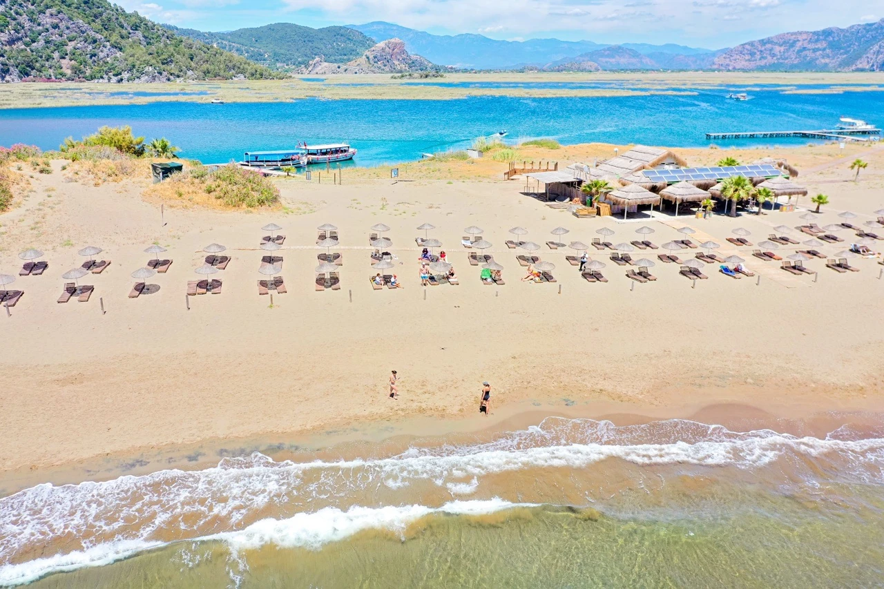 An aerial photograph showcasing the stunning İztuzu Beach in Muğla, Türkiye, where golden sands meet the turquoise waters of the Mediterranean.