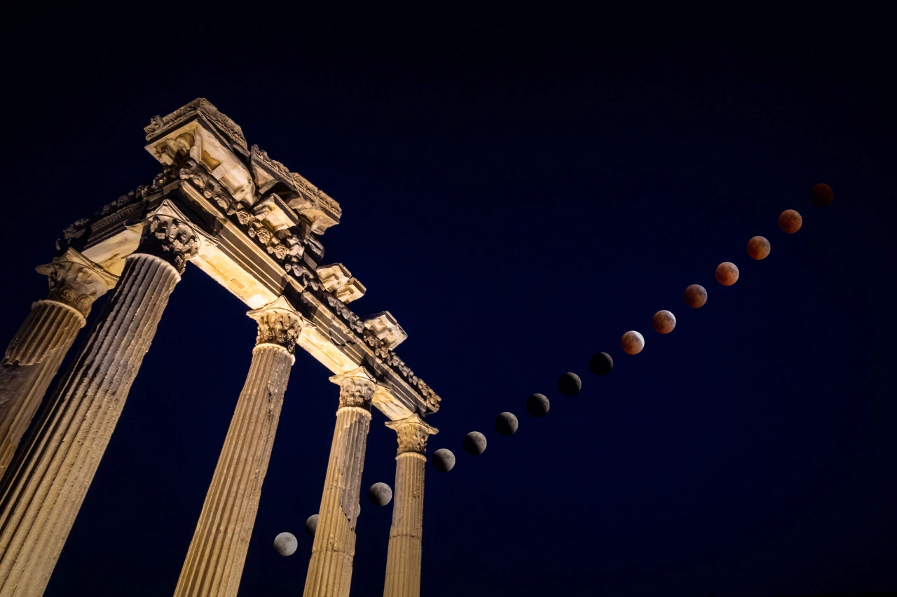 A composite image of a total lunar eclipse unfolding above ancient temple ruins.