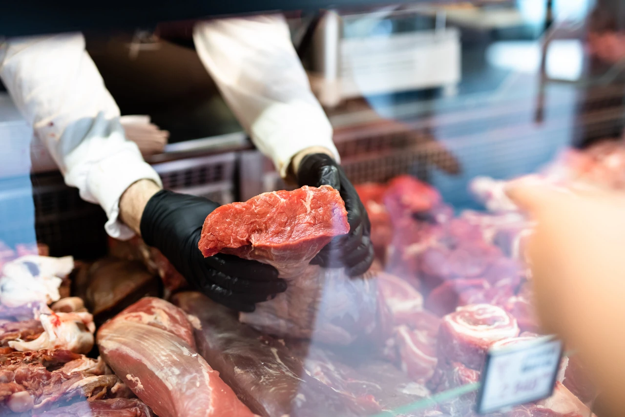 File photo shows a butcher holds a fresh cut of red meat. (Adobe Stock Photo)