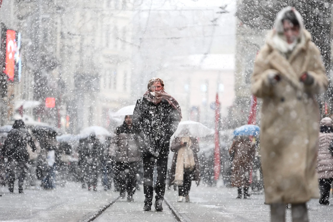 Photo shows people walking with umbrellas.