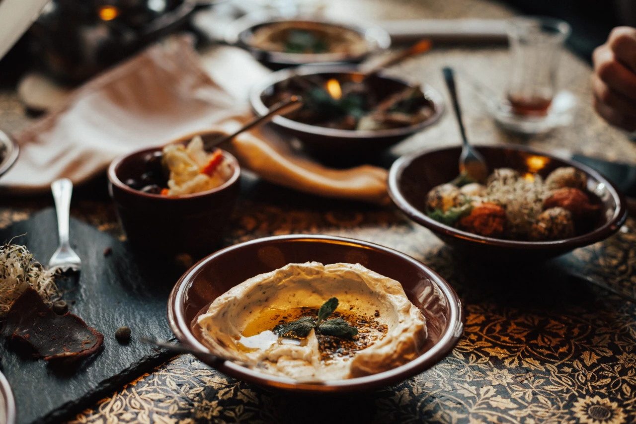 A selection of traditional Syrian appetizers, including hummus, baba ghanoush, and stuffed grape leaves, served on a rustic table.