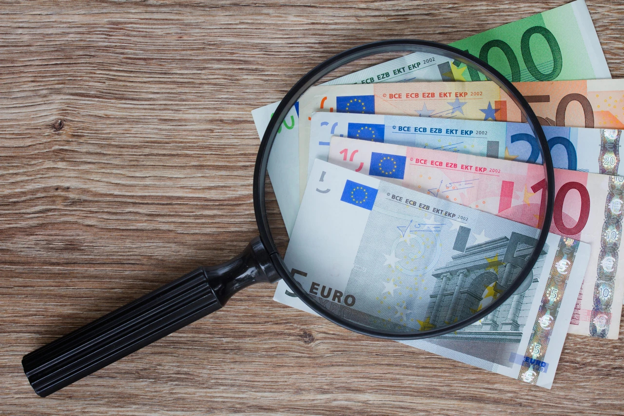 Pile of euro banknotes under magnifying glass