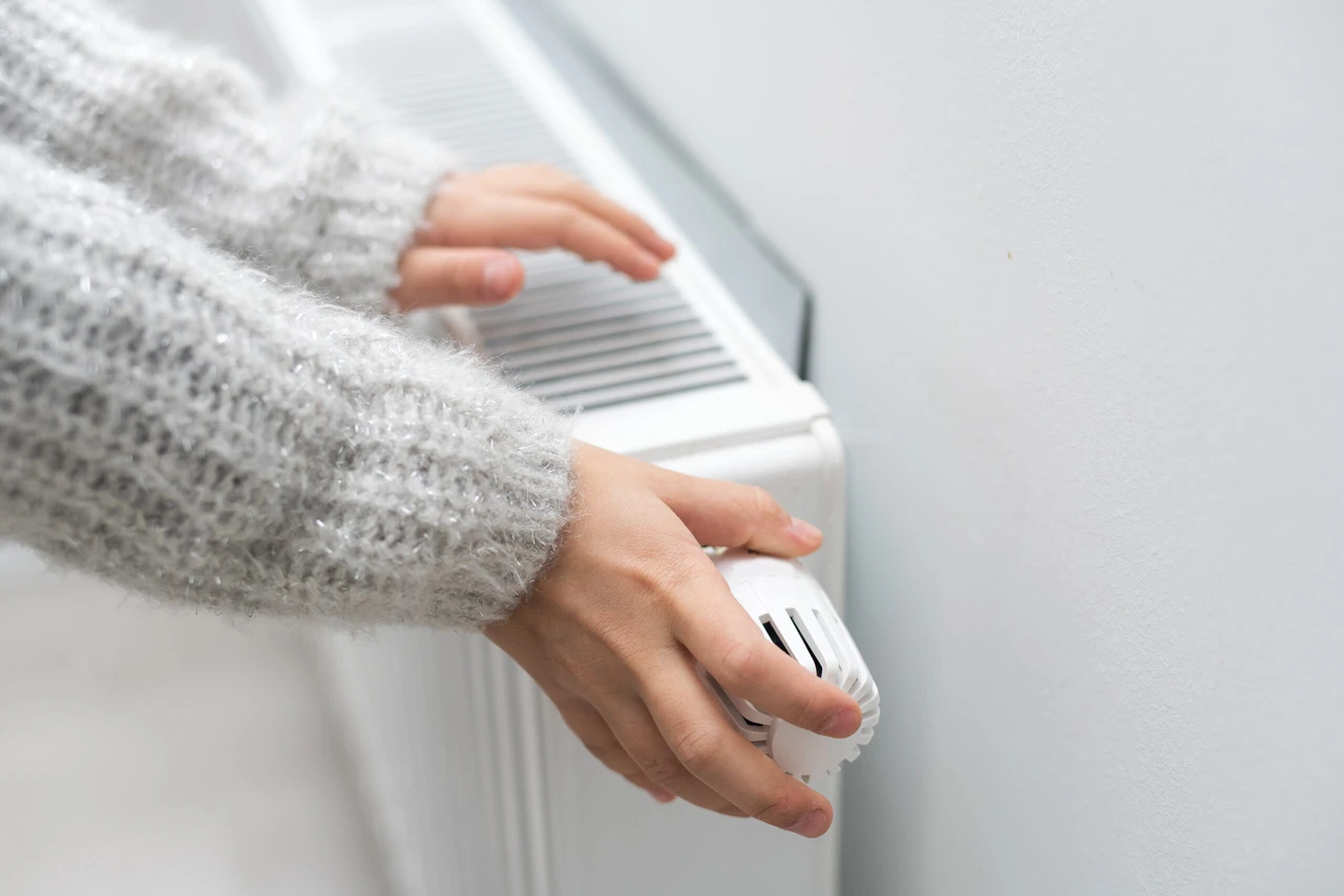 The child's hands warm their hands near the heating radiator. Saving gas in the heating season