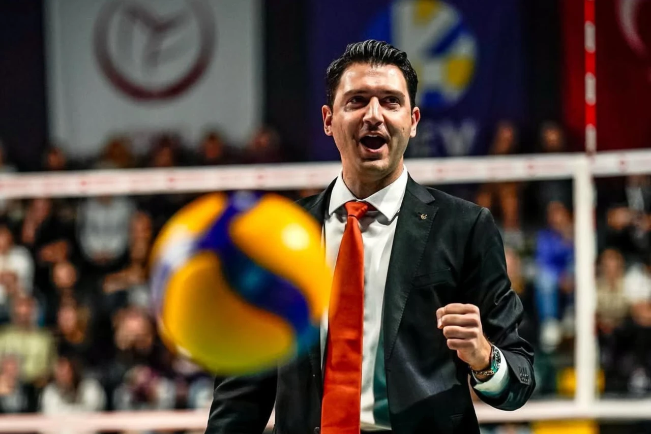 Turkish volleyball coach Ferhat Akbas wearing a black suit and orange tie, intensely directing his team during the Vakifbank Istanbul vs. Eczacibasi Vitra match on December 14, 2024