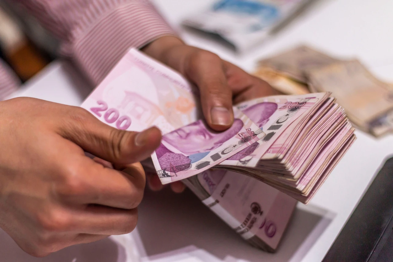 Hands counting a stack of Turkish lira banknotes at desk