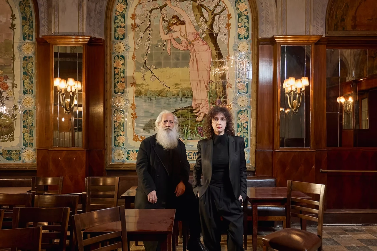 Artists Yasemin Baydar and Birol Demir of :mentalKLINIK stand inside Markiz Pastanesi, posing in front of Art Nouveau murals as part of their Dehsetli Guzel project.