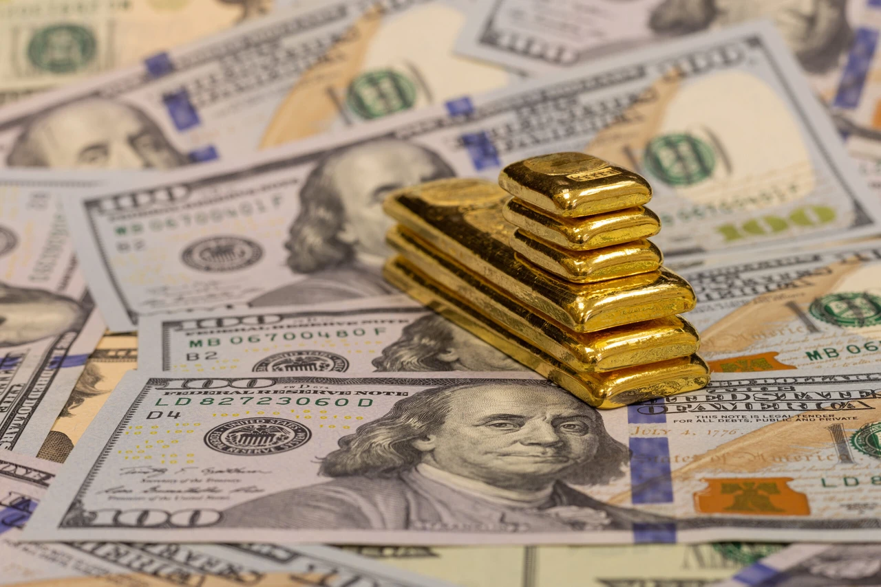 Gold bars stacked on scattered US dollar bills