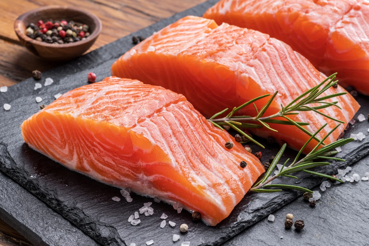 Fresh salmon fillets on black cutting board with herbs and spices