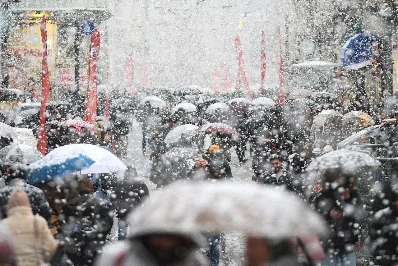 Photo shows people walking with umbrellas.