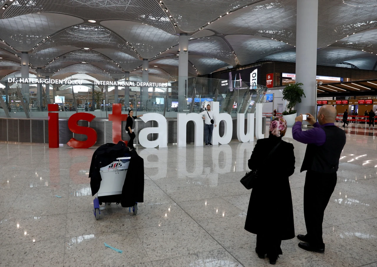 Turkish tourists pose in front of istanbul sign at the airport