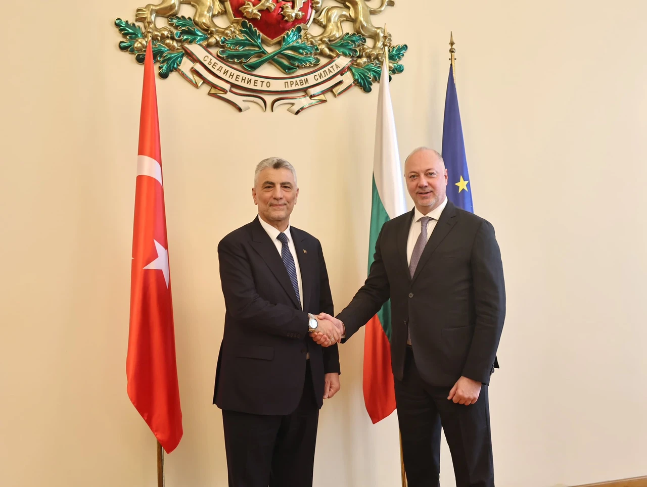 Bolat and Zhelyazkov shake hands in front of national flags