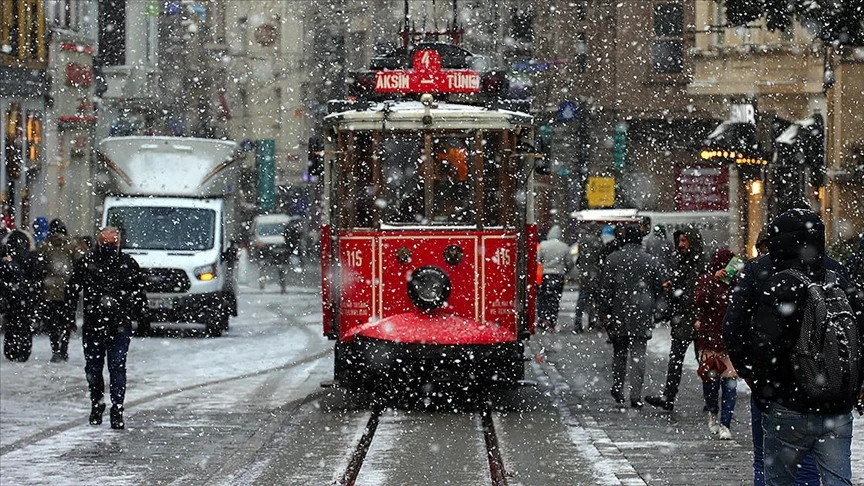 ed historic tram moves through Istiklal Avenue in Istanbul during a snowfall, surrounded by pedestrians in winter clothing