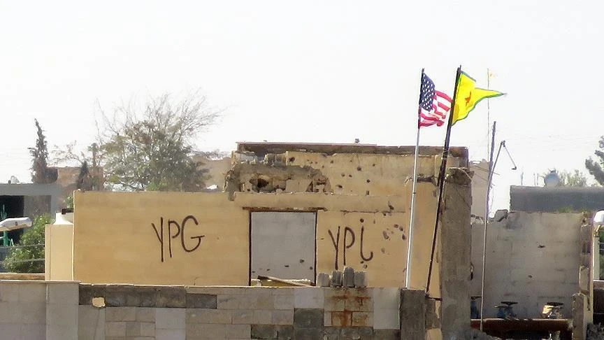 Photo shows US flag along with PKK/YPG flag.