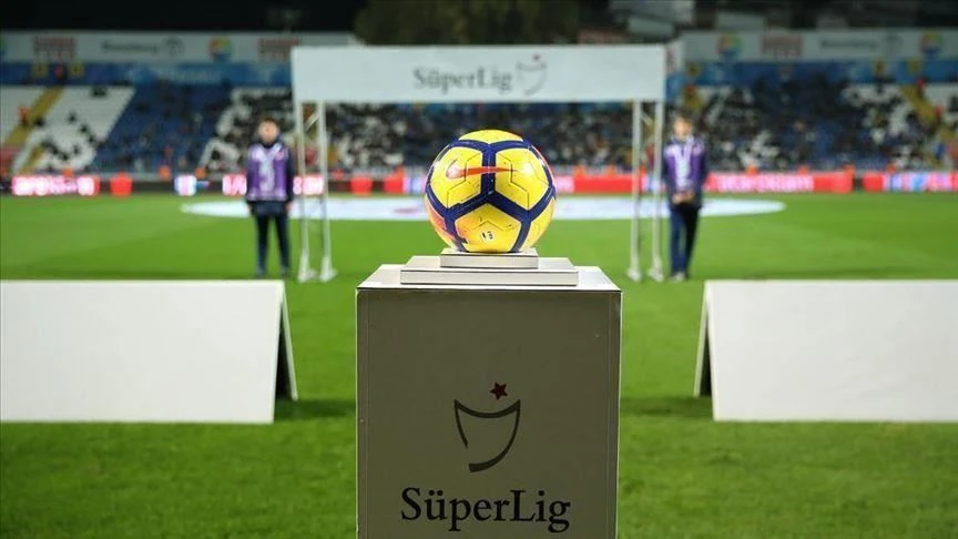 A yellow and blue football sits on a pedestal with the Turkish Super Lig logo in a stadium