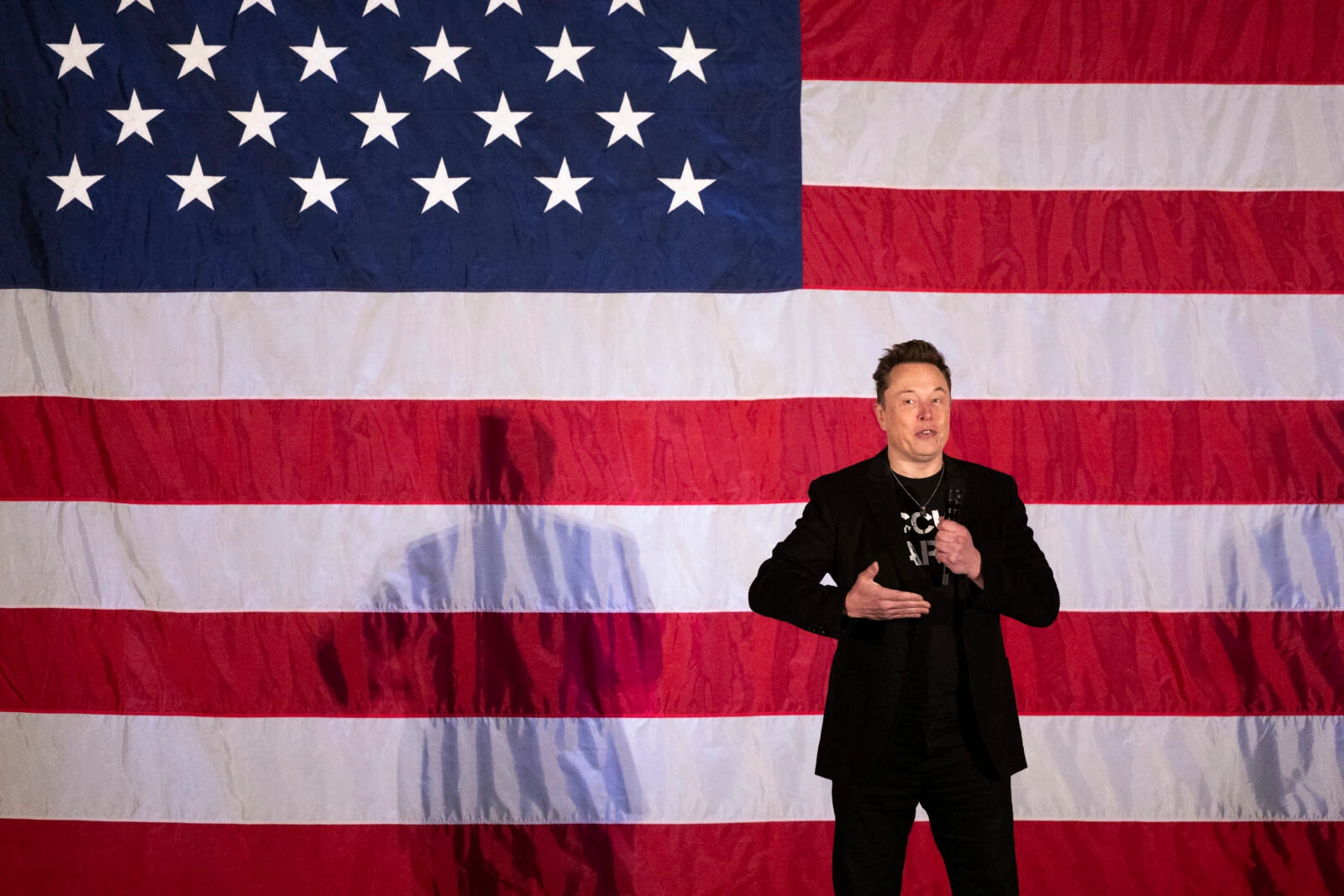 Photo shows elon musk standing in front of a us flag