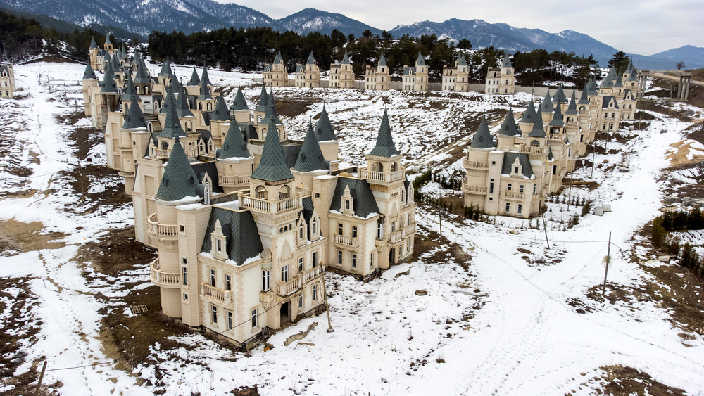 Rows of identical, turreted castles at Burj Al Babas, framed by snowy landscapes in Mudurnu, Bolu, Türkiye