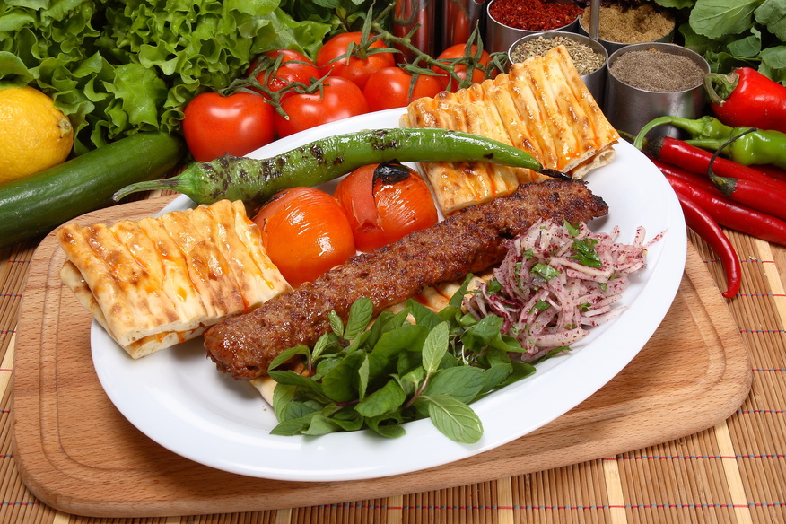 A fiery, charcoal-grilled kebab made with spiced ground lamb, served with fresh herbs and vegetables