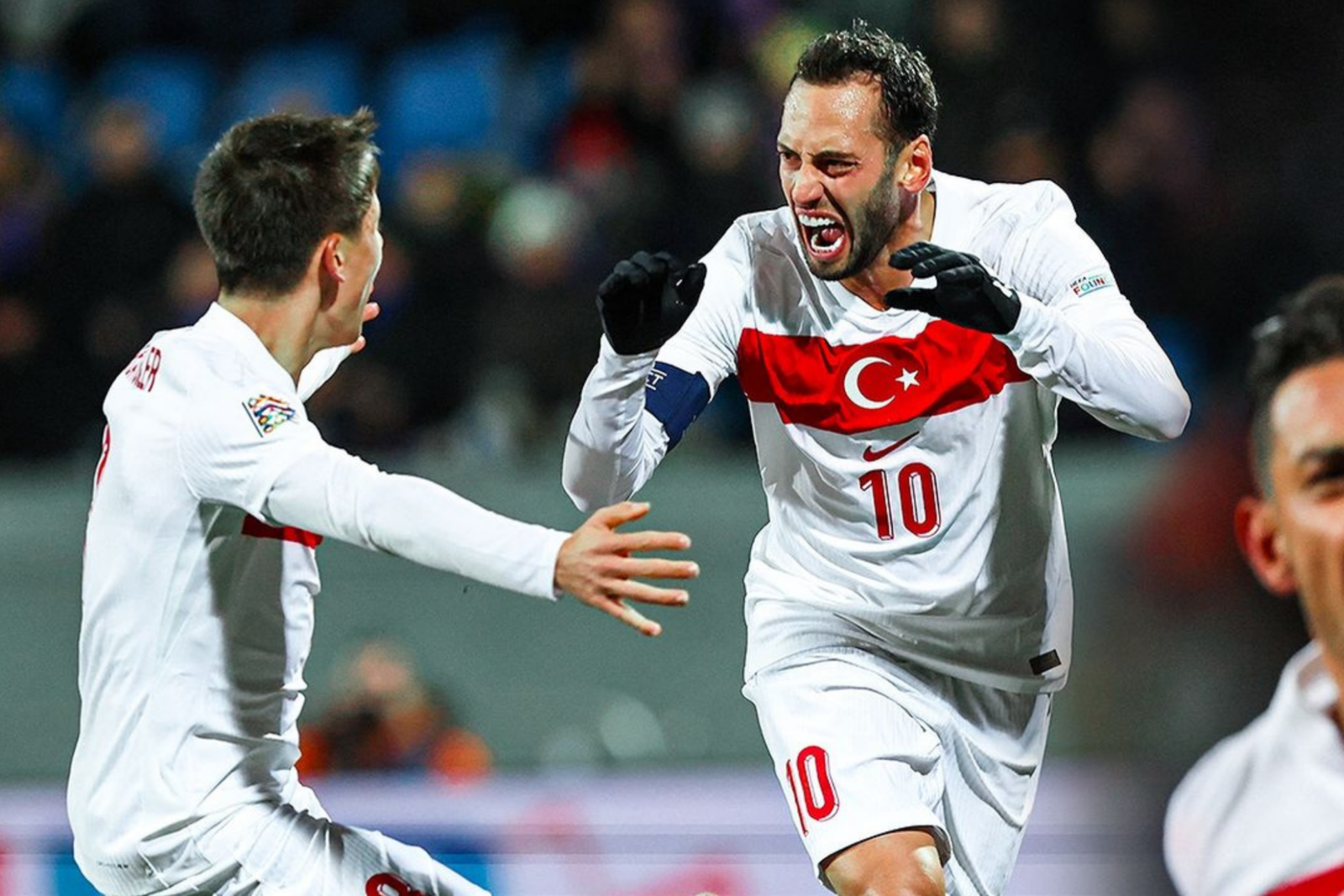 Hakan Calhanoglu smiles at Arda Guler after scoring for Türkiye in a national team match on October 15