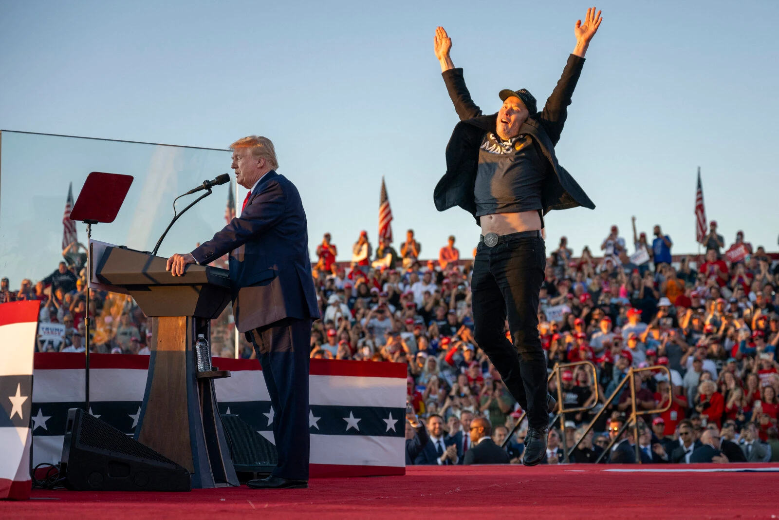 Elon Musk jumps on the stage, next to Trump