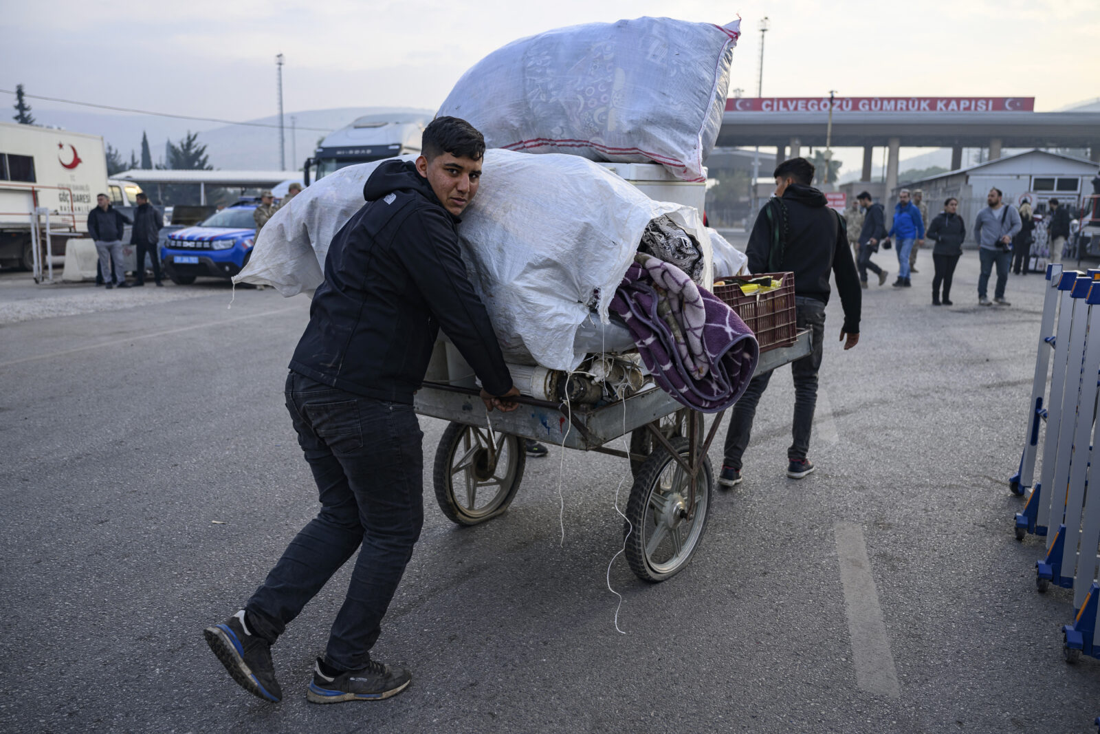 A Syrian man living in Türkiye pushes a cart loaded with his belongings to enter Syria at the Cilvegozu border crossing gate in Reyhanli, Türkiye, Dec. 12, 2024. (AFP Photo)