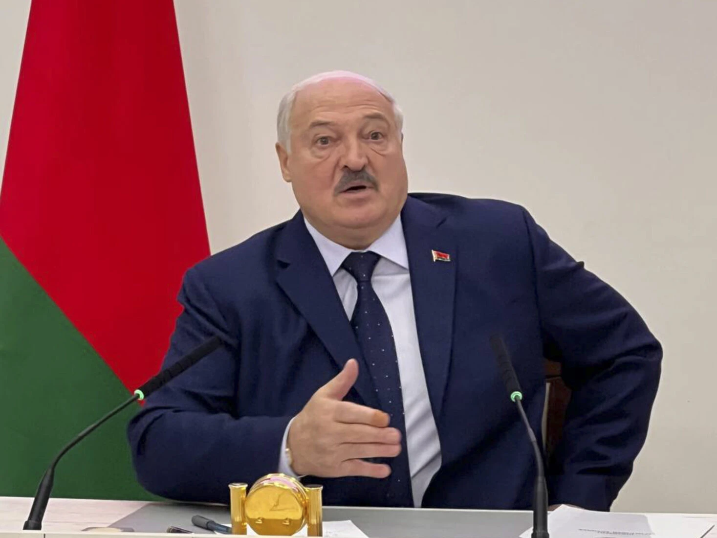 Photo shows Belarus president speaking with a belarus flag on his left