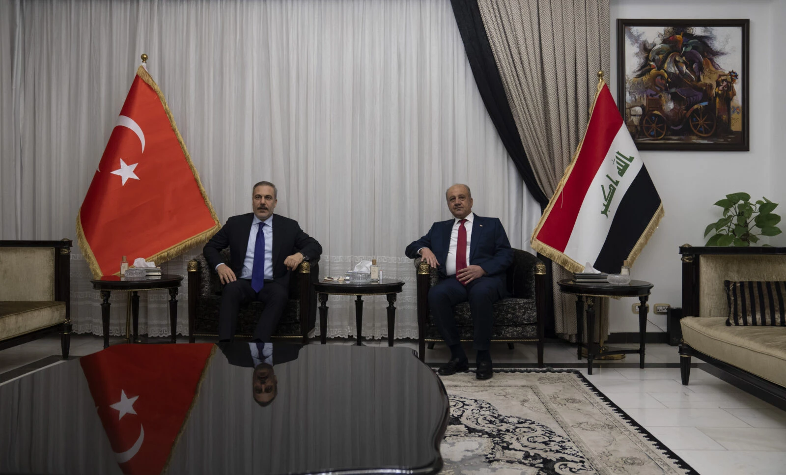 Photo shows Turkey foreign minister hakan fidan sitting beside Iraqi  defense minister Abbasi 