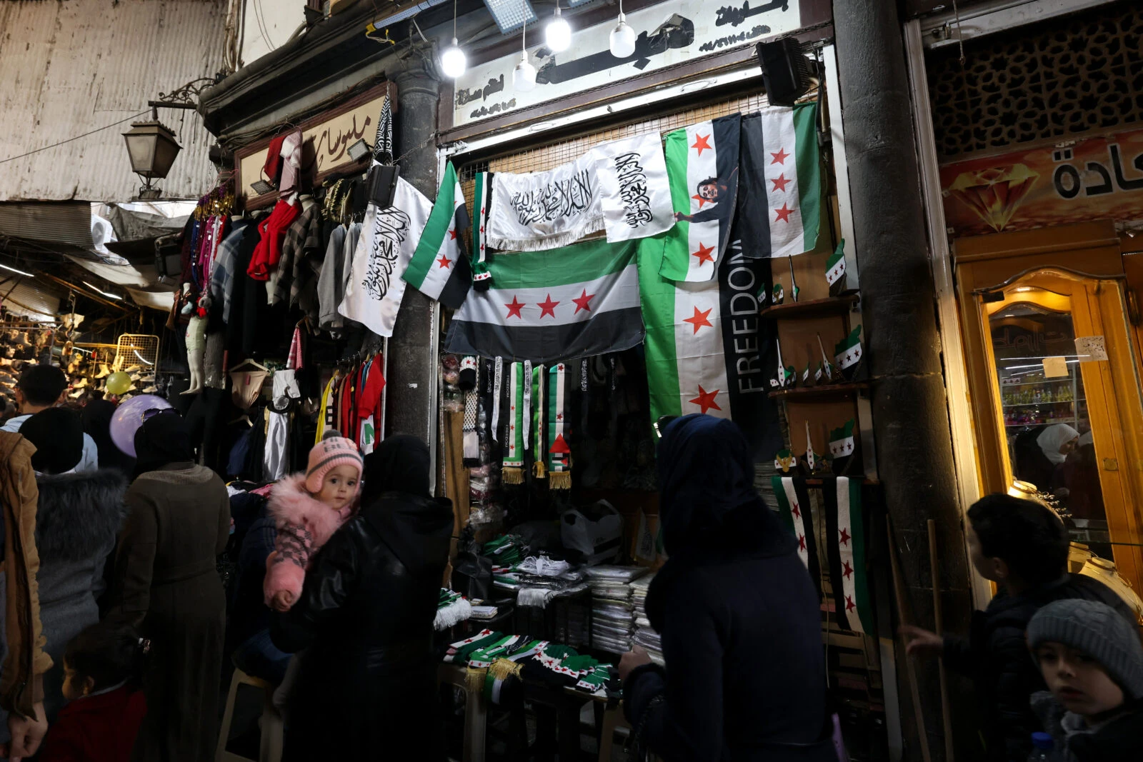 People walk past a shop selling independence-era Syrian flags