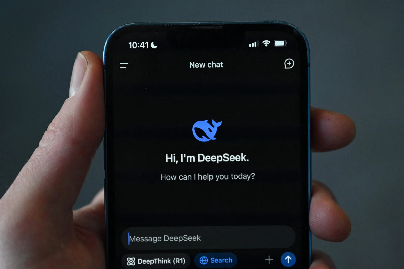 a hand holding a phone showing Deepseek application