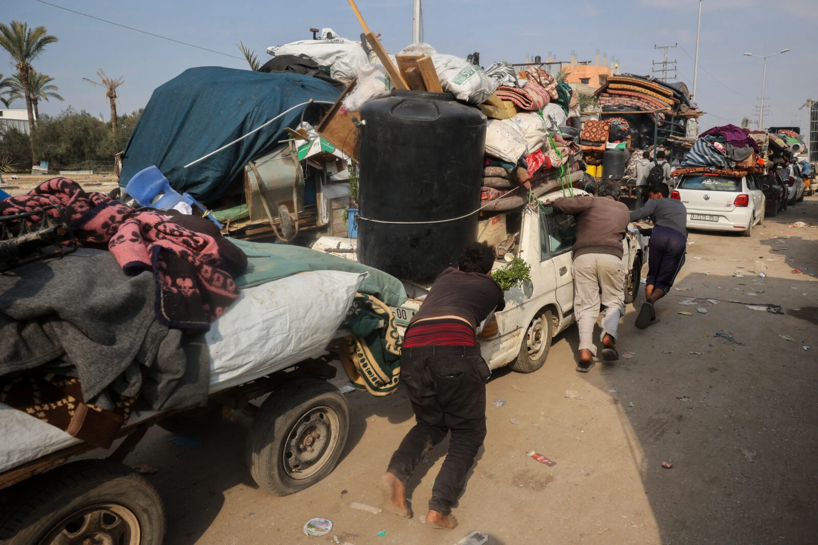 People push a car loaded with personal belongings 