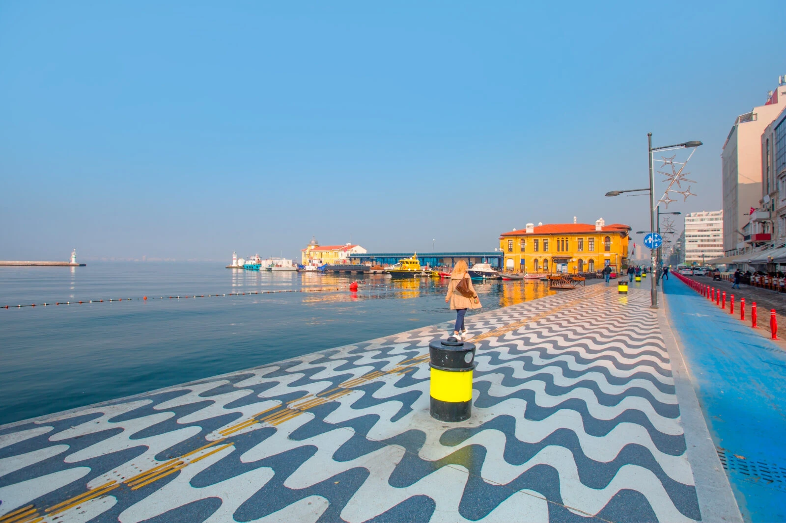 Izmir's Kordon waterfront with black-and-white wave mosaics, calm sea waters, historic buildings, and a clear sky