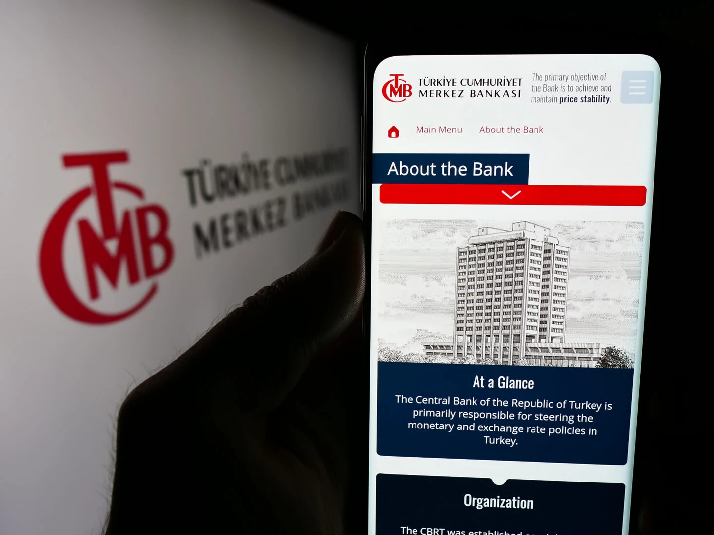 a person holds a smartphone displaying the Central Bank of the Republic of Türkiye's (CBRT) website