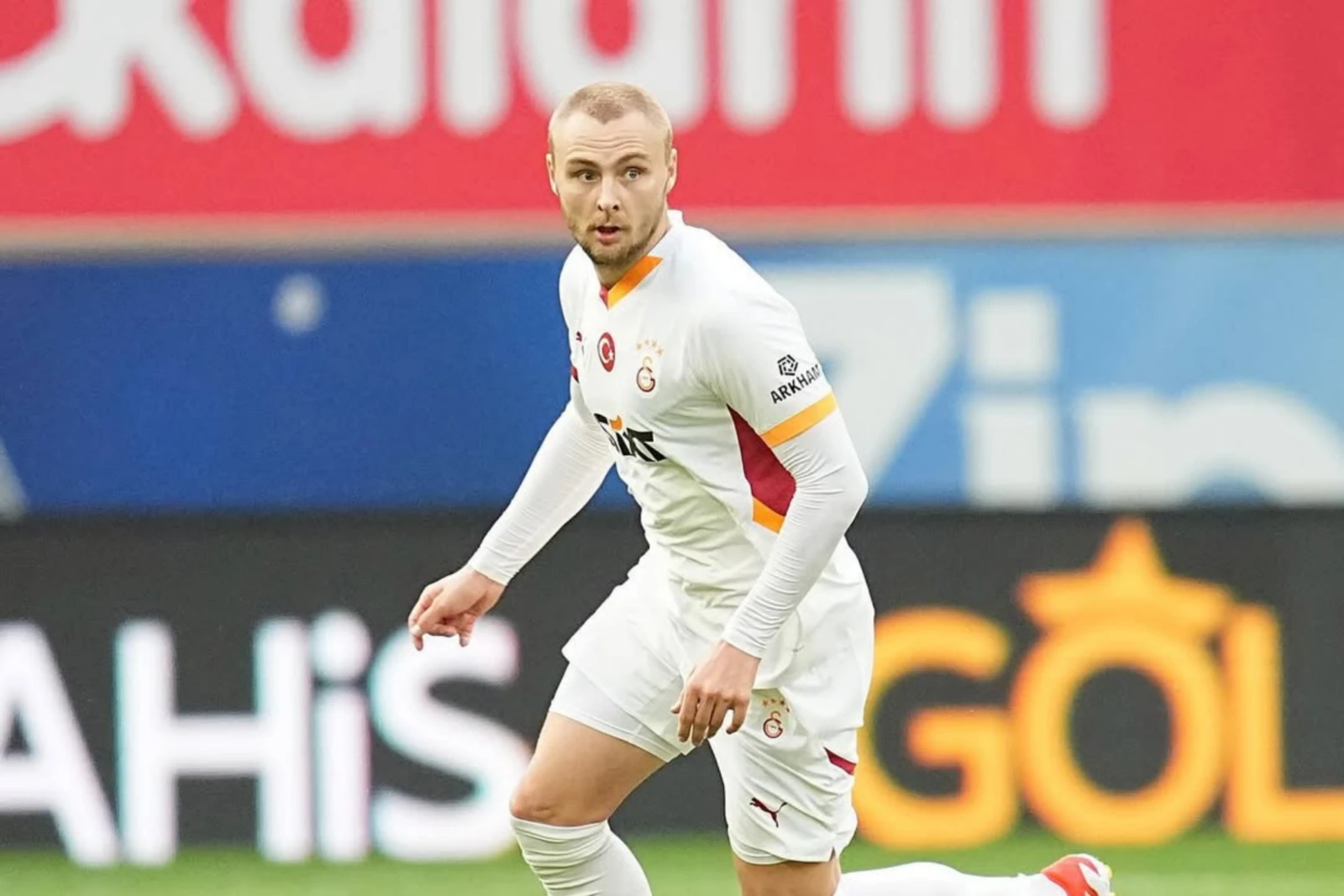 Victor Nelsson, dressed in Galatasaray's white away jersey, stands in a defensive stance near the goal during a match