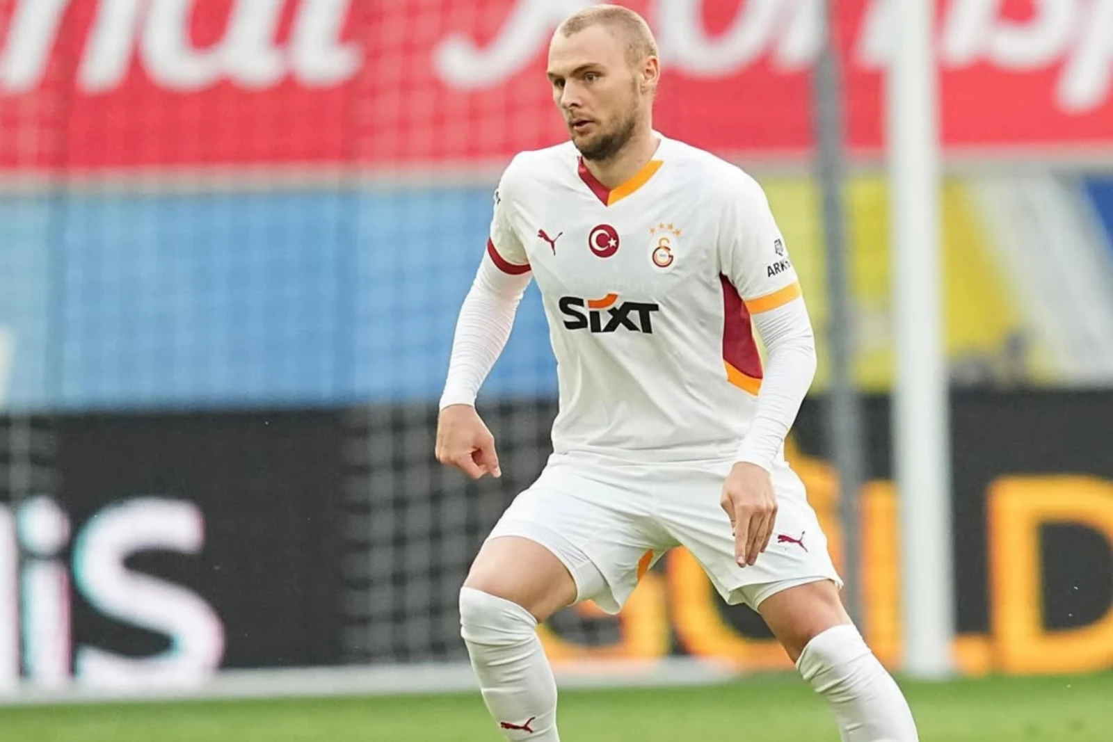 Victor Nelsson, wearing Galatasaray's white away kit, focuses on the game while running during a match