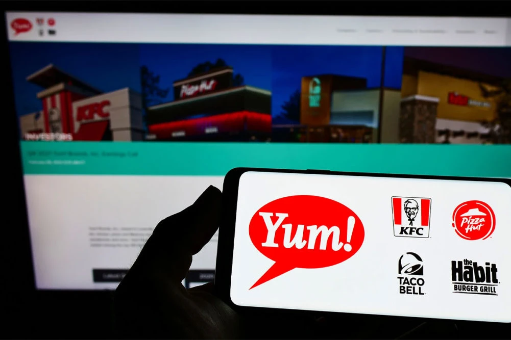 A smartphone screen displays the Yum! Brands logo