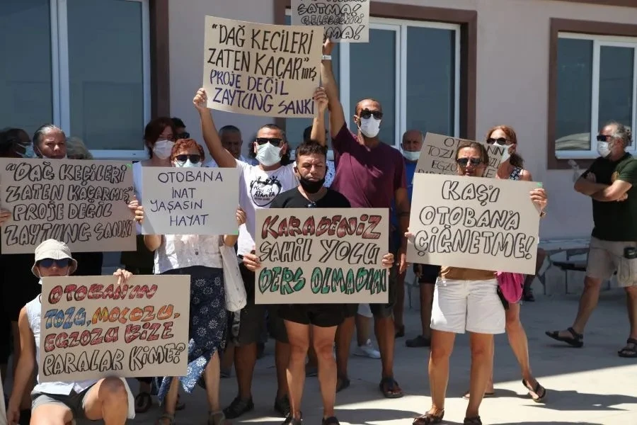 Protesters in Türkiye's Kas holding signs opposing the Finike-Kalkan highway project