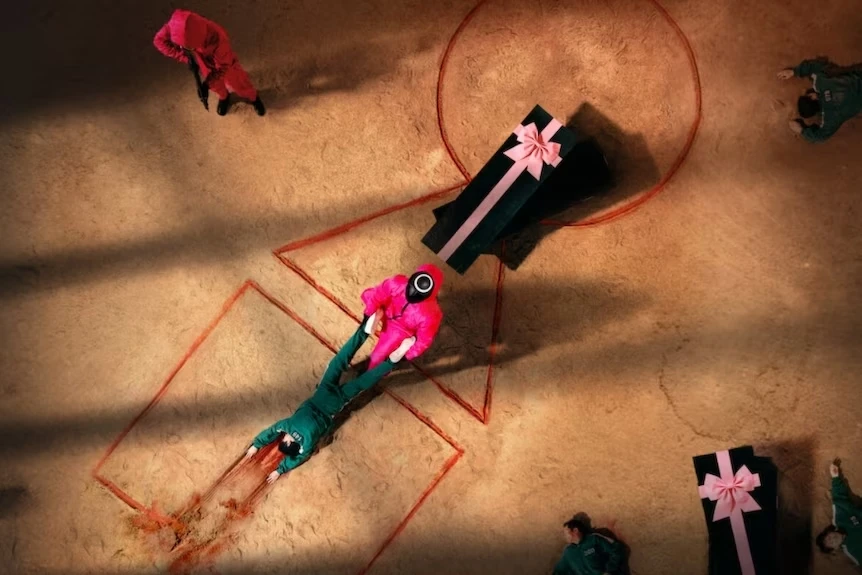 A still from Netflix's Squid Game shows a contestant being dragged across the ground as part of a deadly competition