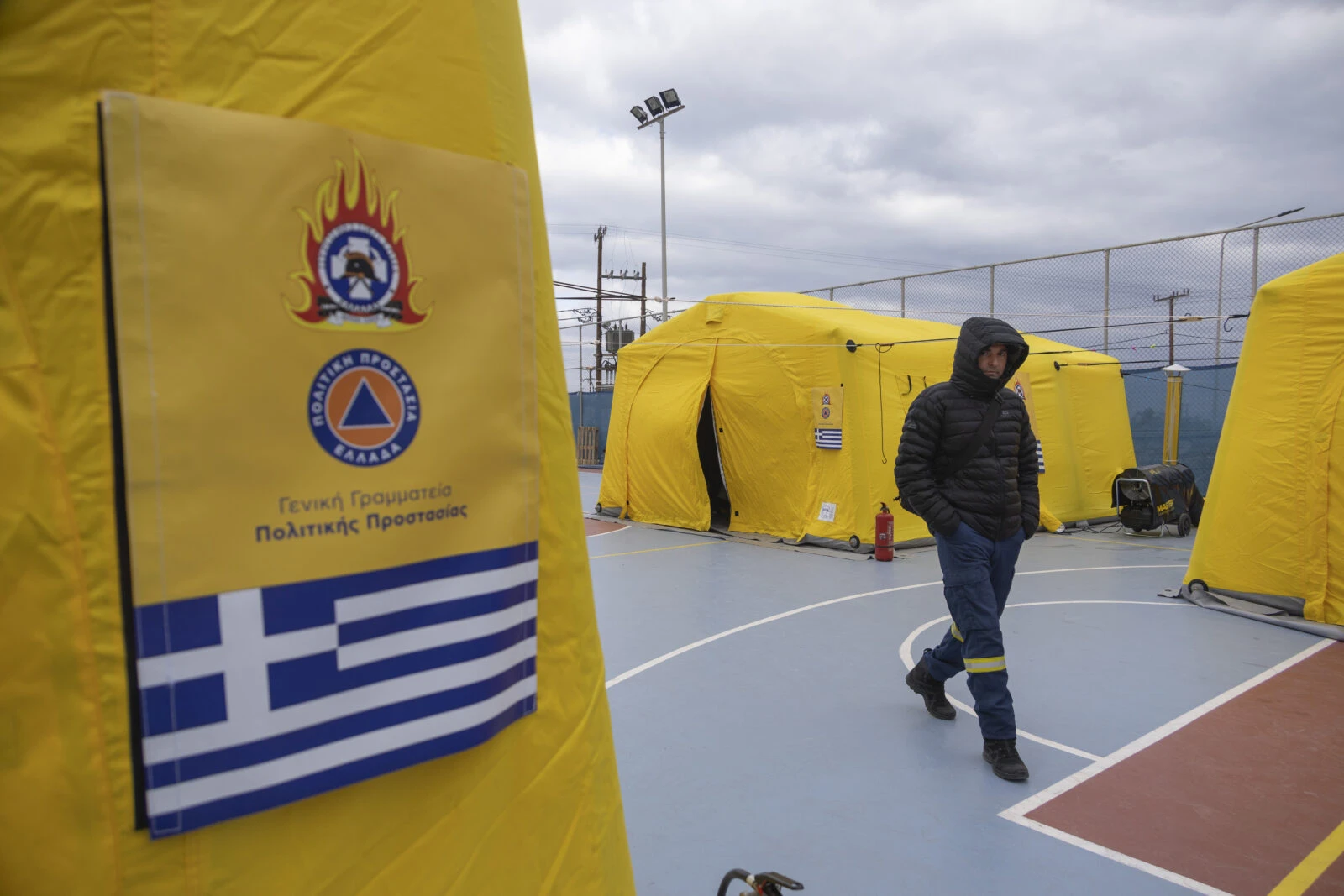 A firefighter walking near emergency tents set up in Fira, Santorini, for disaster response teams.