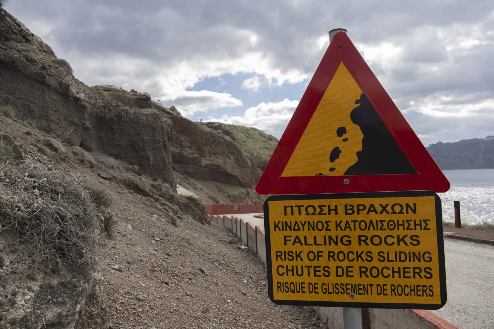 A caution sign warning of falling rocks near the cliffs of Ammoudi in Santorini.