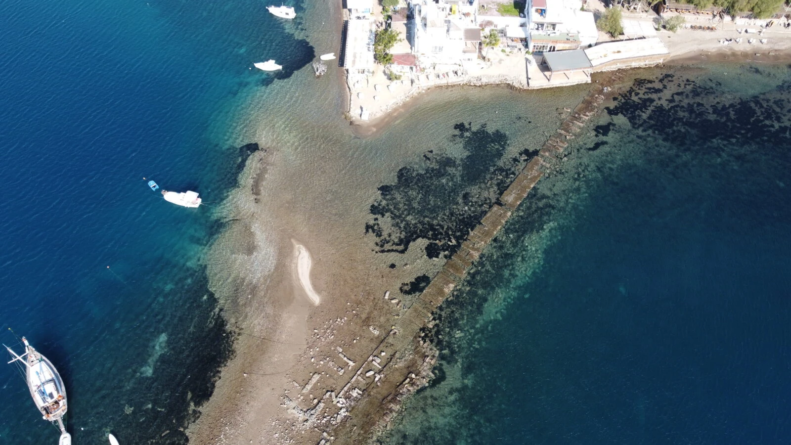 Aerial view of the historical city wall remnants extending to Rabbit Island in Bodrum, Muğla, revealed by the receding sea.