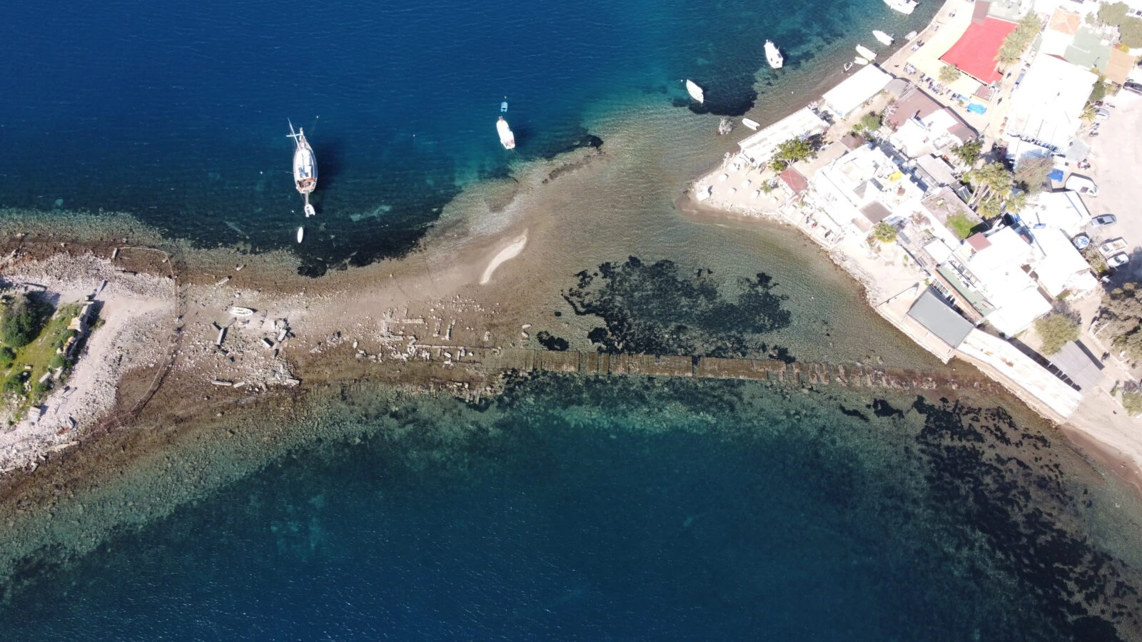 Aerial view of the historical city wall remnants extending to Rabbit Island in Bodrum, Muğla, revealed by the receding sea.