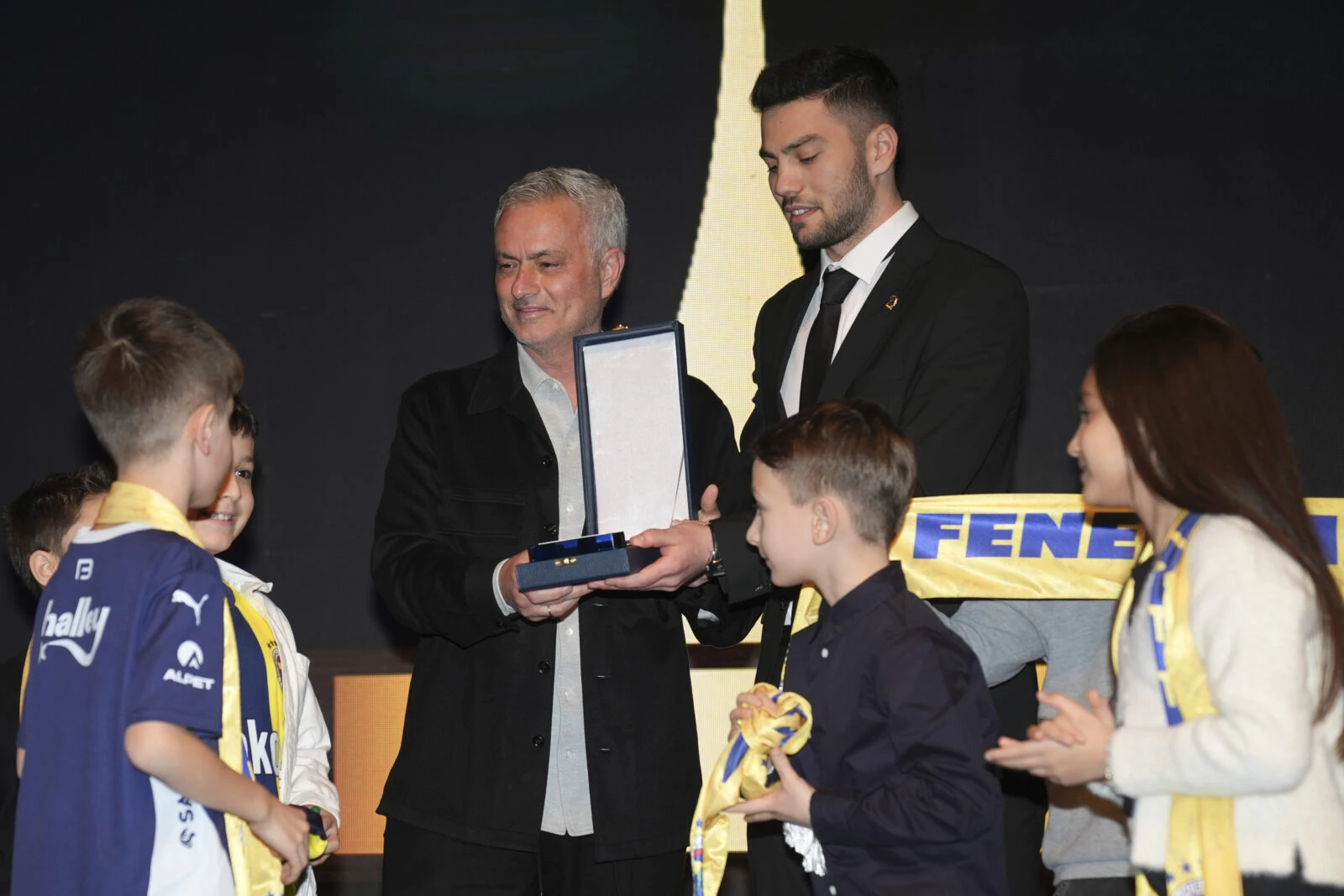 Jose Mourinho, Fenerbahçe's head coach, holds the "Project of the Year" award at the 2024 Aydınlık Gelecek Awards ceremony, surrounded by children and members of 1907 ÜNİFEB.