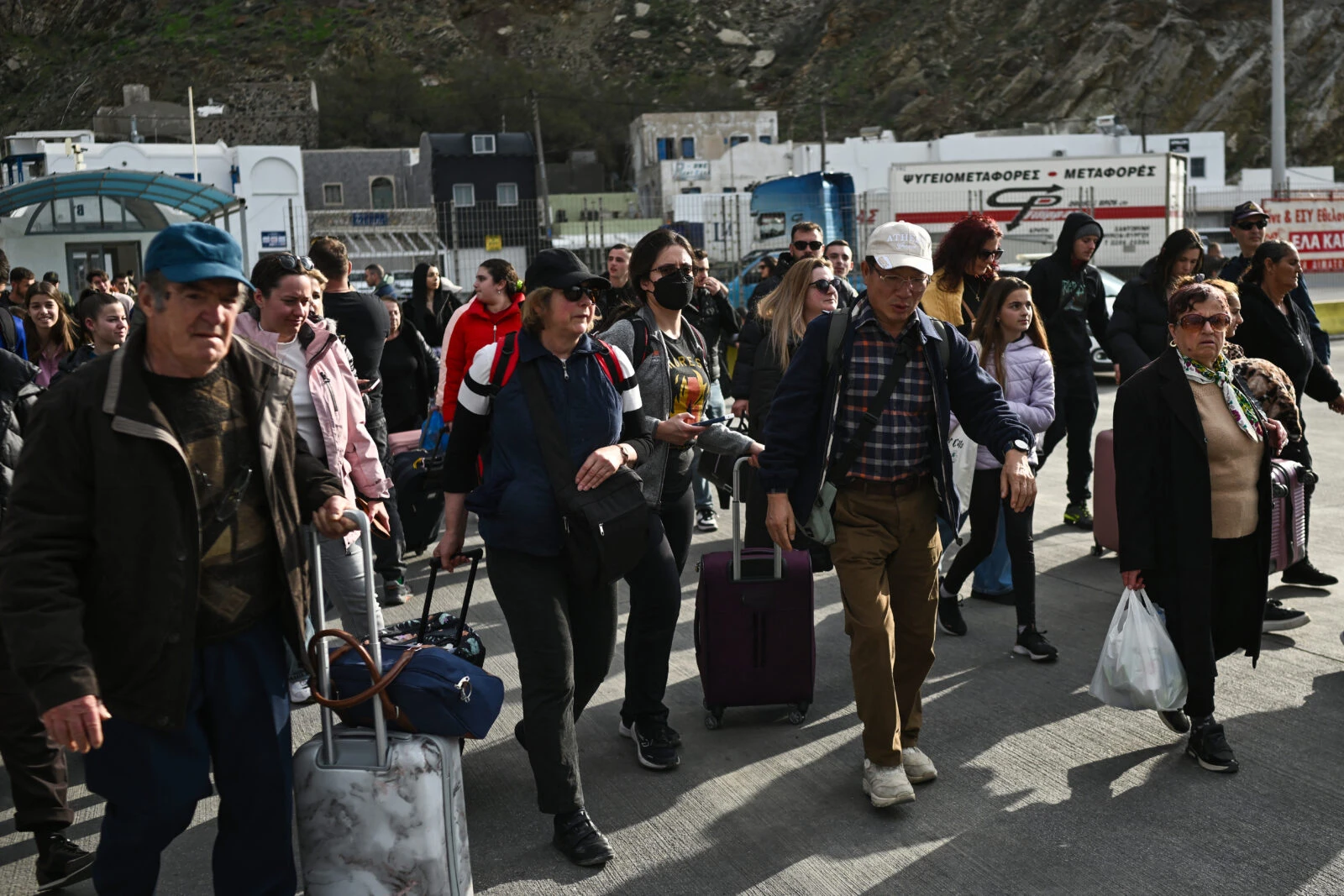 People walk to embark a ferry at the port on the Greek Island of Santorini